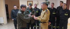 Zdjęcie przedstawia harcerzy, którzy przekazują Światło Pokoju Zastępcy KP PSP w Pruszczu Gdańskim, w tle stoją strażacy z JRG w Pruszczu Gdańskim