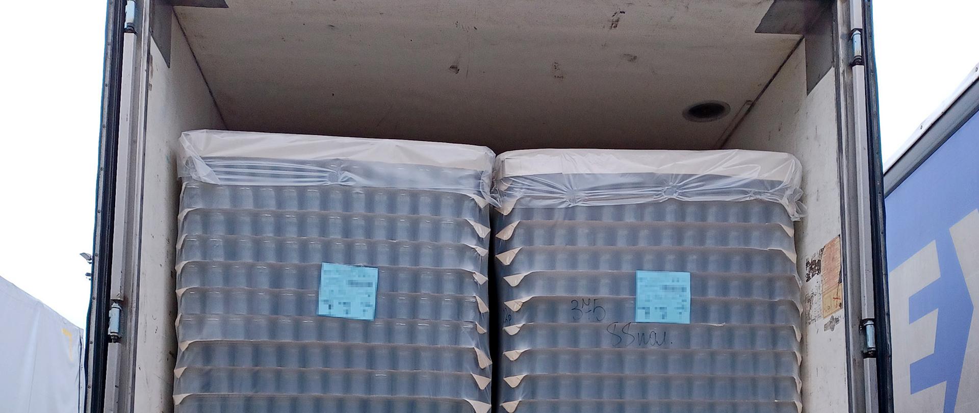 Otwarty tył naczepy z ładunkiem słoików.