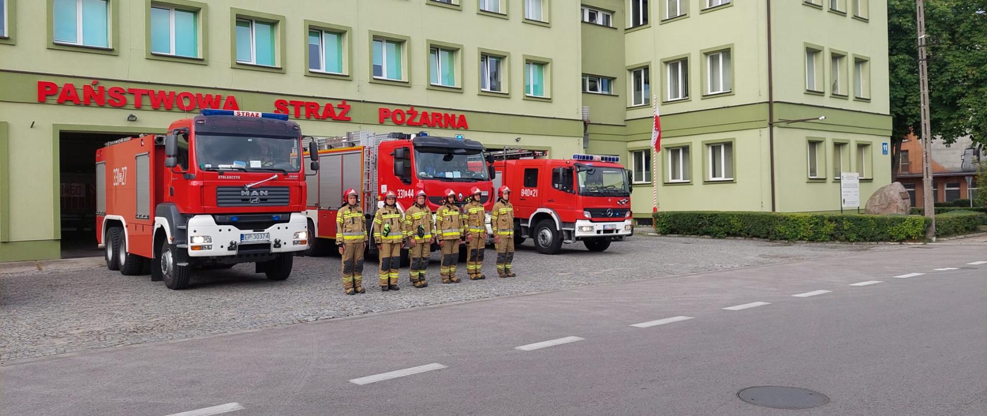 Strażacy JRG przed wozami bojowymi na tle budynku KM PSP Piotrków Tryb podczas uczczenia 78 rocznicy wybuchu Powstania Warszawskiego