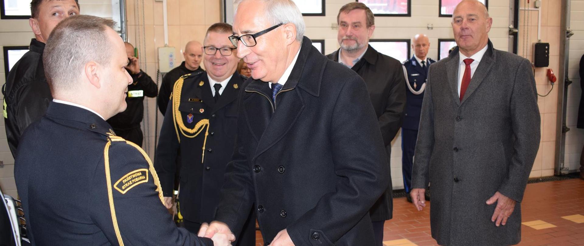 Poseł Kazimierz Smoliński gratuluje p.o. Dowódcy JRG Tczew przekazania samochodu, z tyłu prezydent miasta Tczew,, Starosta Tczewski i Z-ca Pomorskiego Komendanta Wojewódzkiego. Wnętrze garażu.