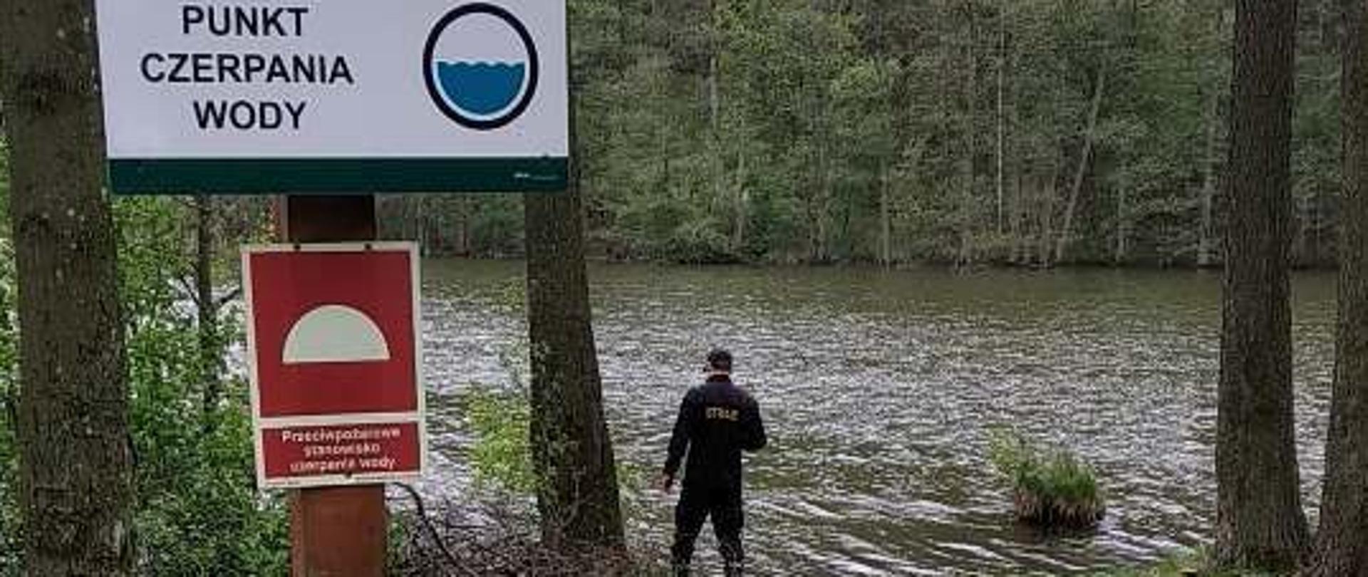 Widok strażaka kontrolującego punkt czerpania wody.
