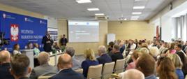 grupa słuchaczy, samorządowcy, siedzą na krzesłach słuchają wypowiedzi wojewody 