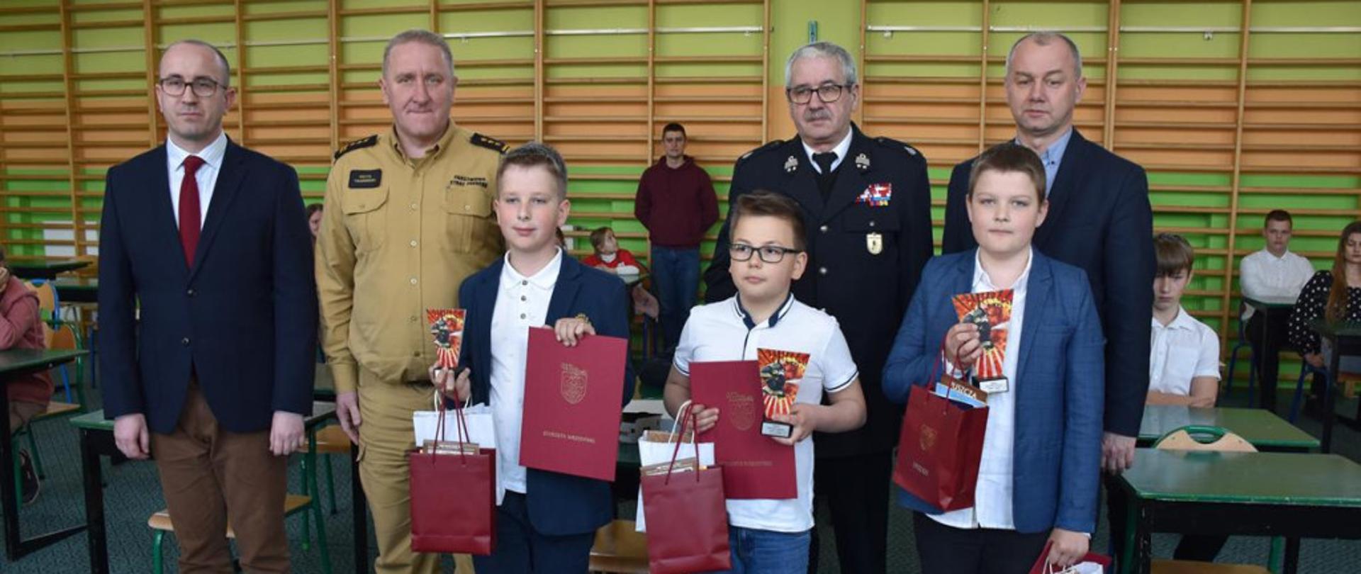 Zdjęcie przedstawia od lewej burmistrza Pyzdr potem Komendanta Powiatowego PSP we Wrześni, przedstawiciela OSP, Vicestarostę Wrzesińskiego oraz trzech laureatów z nagrodami