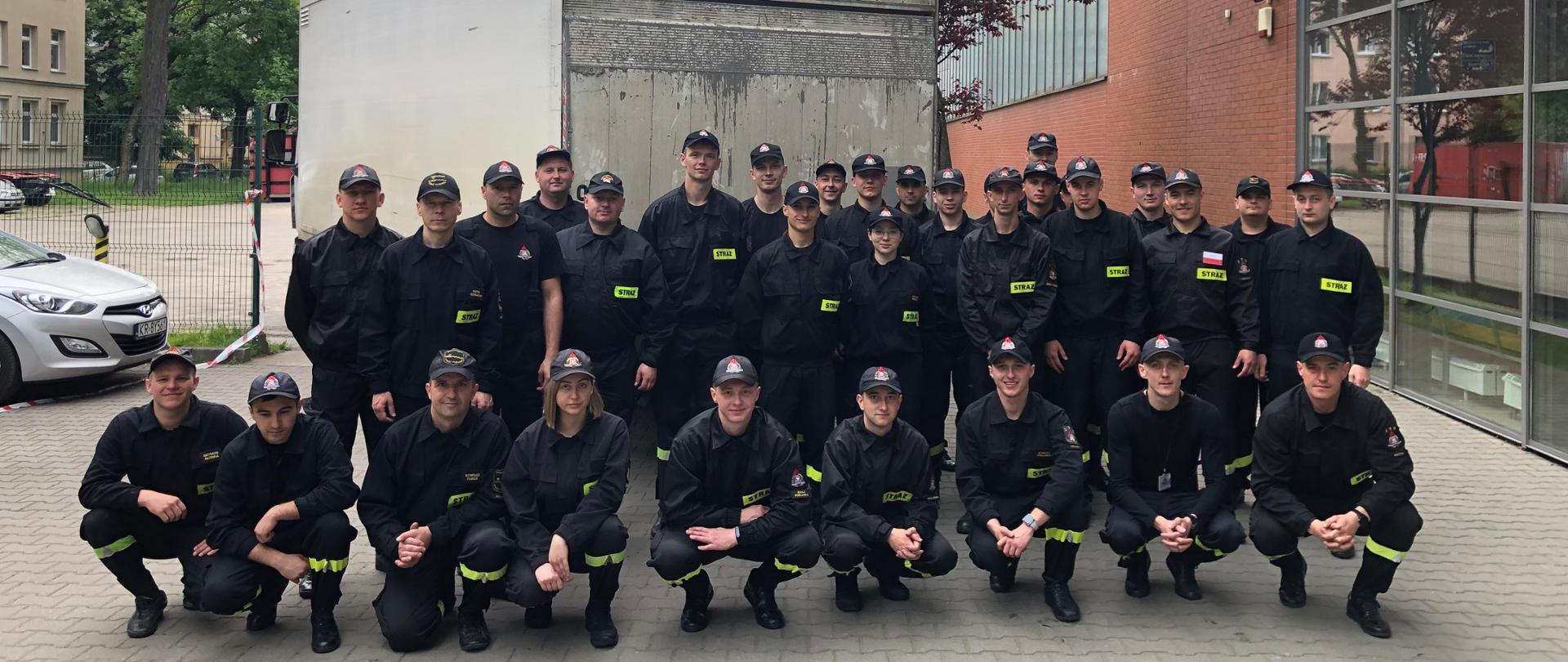 Pamiątkowe zdjęcie strażaków ustawionych przed białym samochodem dostawczym. 