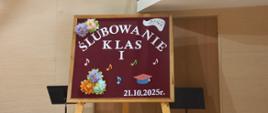 Na zdjęciu widnieje tablica informująca o ślubowaniu klas pierwszych. Na całej tablicy rozmieszczone są nutki oraz kwiaty, a na dole tablicy jest zamieszczona data.