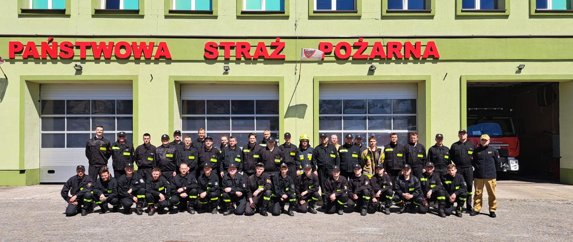 Uczestnicy szkolenia podstawowego ratowników OSP po zdanym egzaminie na tle budynku Komendy Miejskiej PSP w Piotrkowie Tryb.