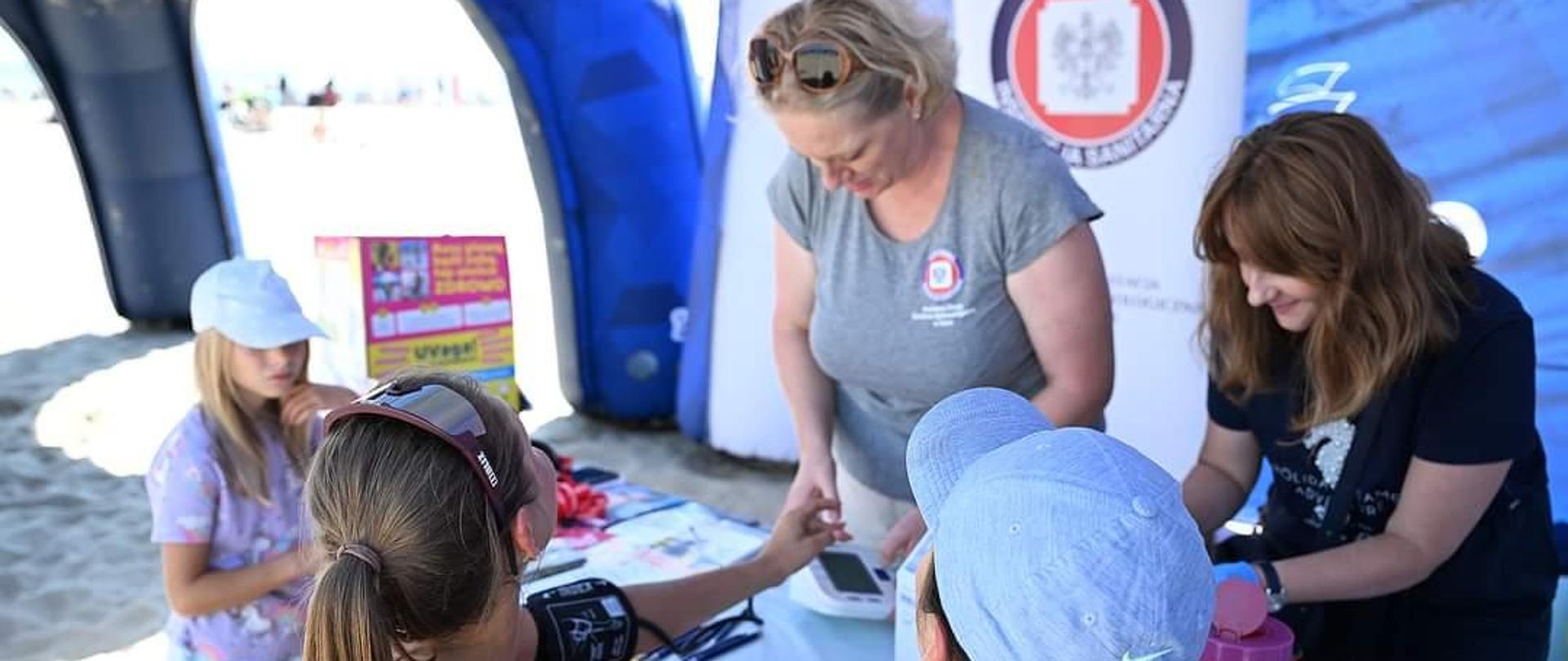 Na zdjęciu widać osoby w punkcie informacyjnym PSSE w Gdyni zlokalizowanym na plaży w Gdyni