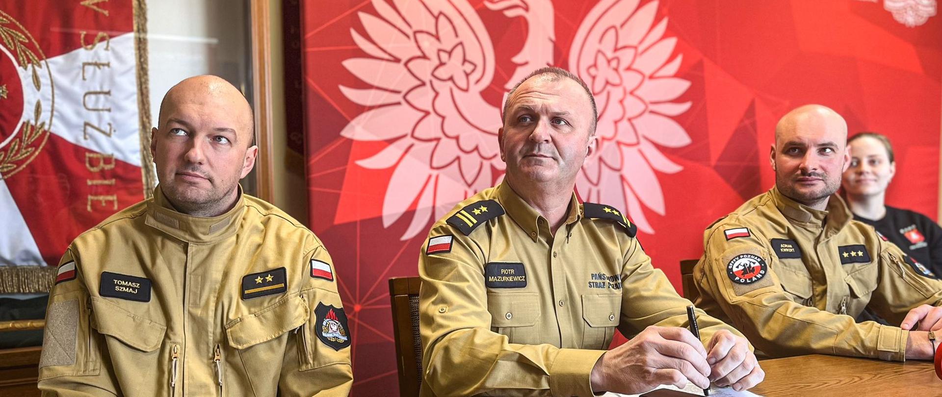 Strażacy biorący udział w konferencji siedzą przy stole.