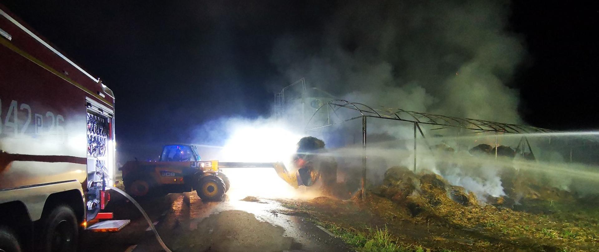 Koparka przewożąca baloty słomy.