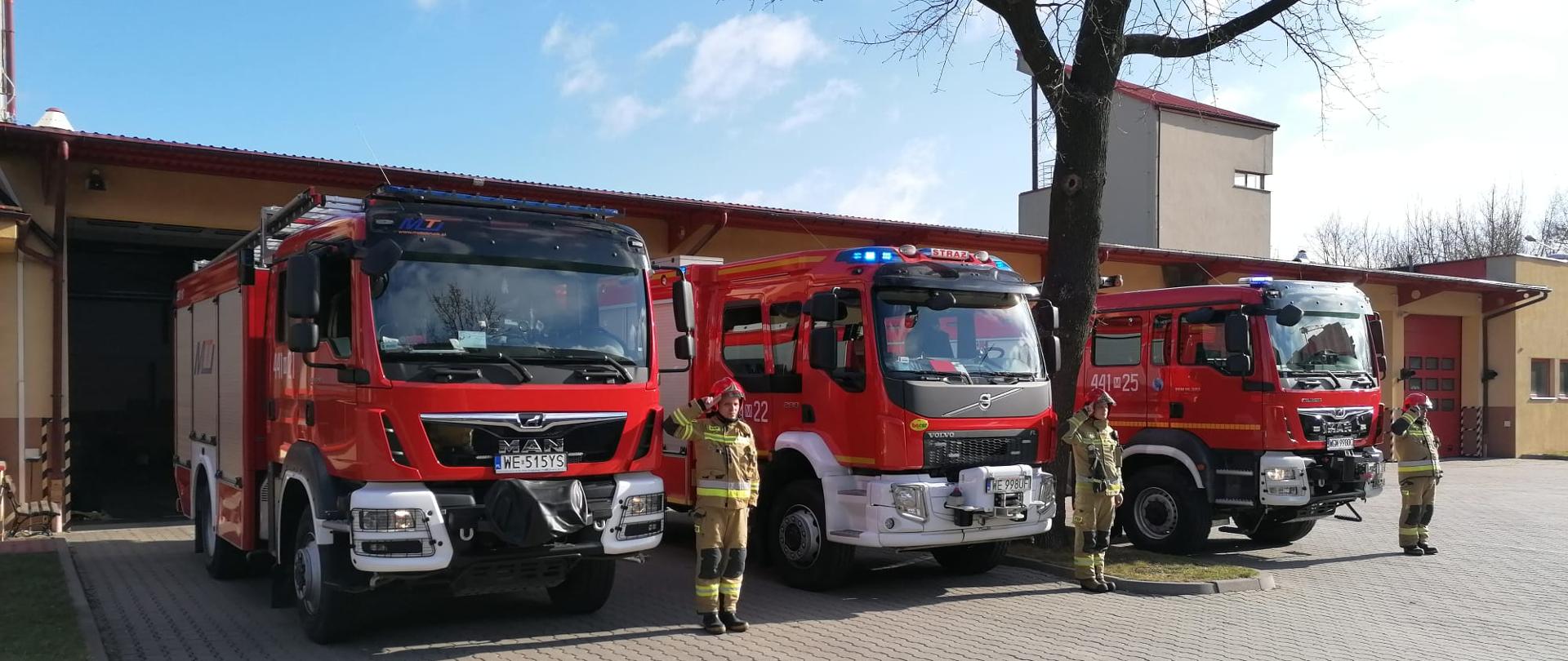 Strażacy oddają hołd dla ofiar katastrofy pod Smoleńskiemze mają włączone sygnalświetlne, przy nich stoją kierowcy, ktoy salutują. 