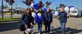 Cztery kobiety w granatowych bluzach stoją z balonami i koszykami 