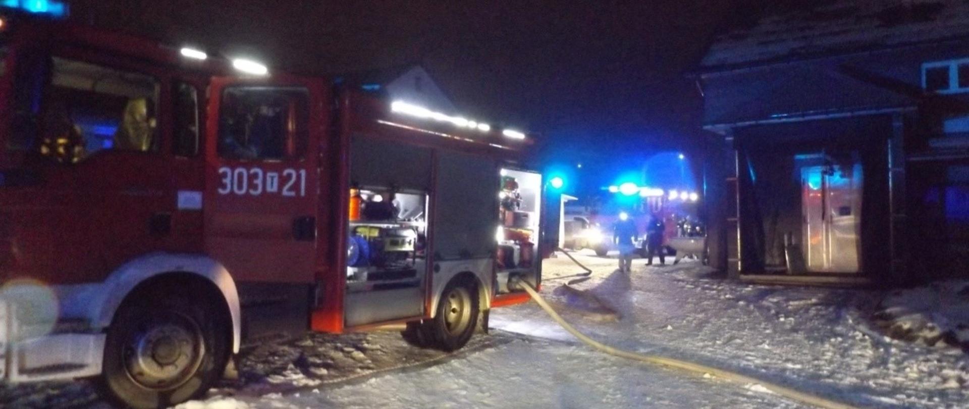 Na zdjęciu widoczne są samochody pożarnicze biorące udział w gaszeniu pożaru kotłowni. Z pojazdów rozwinięte zostały linie główne, gaśnicze i zasilające.