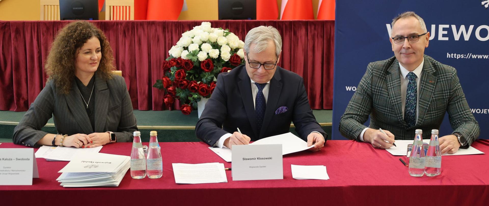 Przy stole prezydialnym zasiadają (od prawej) dyrektor Wydziału Infrastruktury i Nieruchomości OUW, Wojewoda Opolski oraz przedstawiciel samorządu. Wojewoda podpisuje umowę.