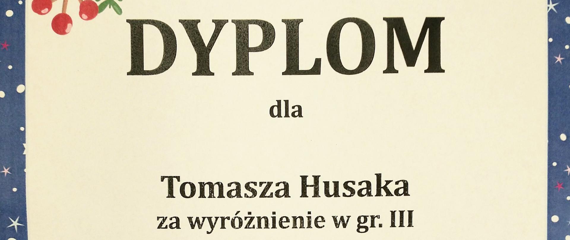 Dyplom kolor kremowy granatowa obwódka z gwiazdkami i śnieżynkami w lewym górnym rogu symbol jarzębiny czerwonej z zieloną gałązką oraz bombką choinkową na samym dole zaprzęg 6 brązowych reniferów ciągnących czerwone sanie z czerwonym Mikołajem siedzącym z rozłożonymi rękoma z tyłu zielony worek prawdopodobnie z prezentami od góry napis agencja artystyczna Modran państwowa szkoła muzyczna pierwszego i drugiego stopnia imienia Szafranków w Rybniku dyplom dla Tomasza Husaka za wyróżnienie w grupie 3 w XVII mikołajkowym konkursie gitarowym dla dzieci poniżej podpisy jurorów dr Miłosz Mączyński magister Katarina Wieczorkowa magister Jan Pajonk magister Marceli Kubica magister Radosław Wieczorek, Rybnik 9 grudnia 2023