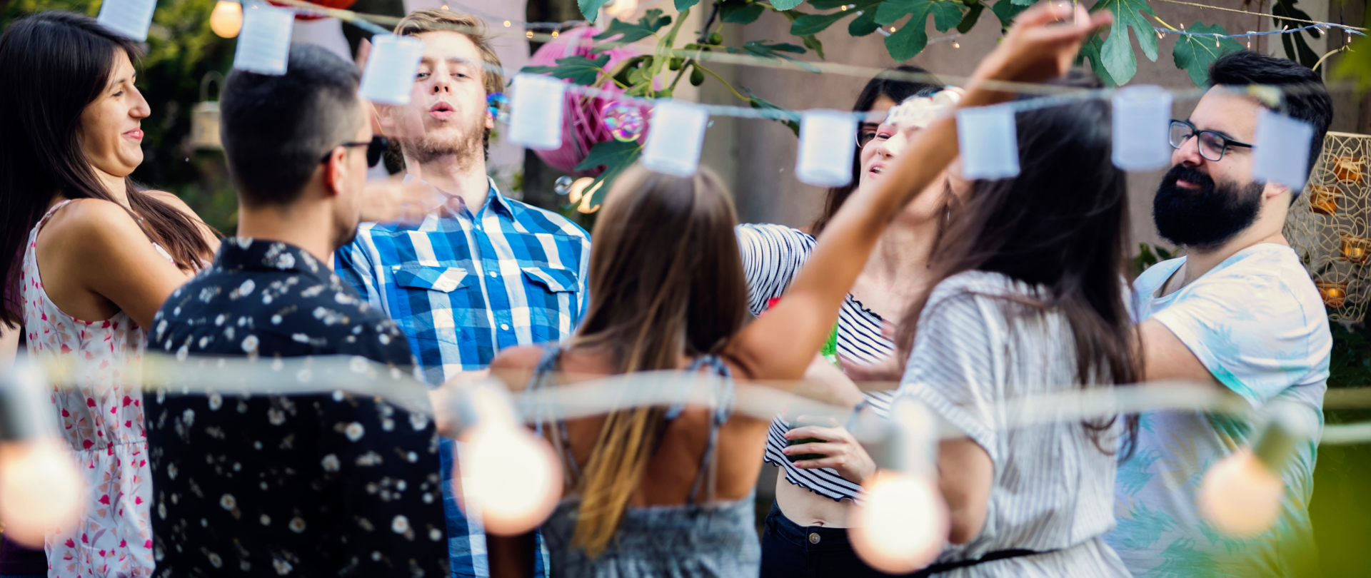 Zdjęcie grupy uśmiechniętych młodych ludzi podczas zabawy na zewnątrz, świętują.