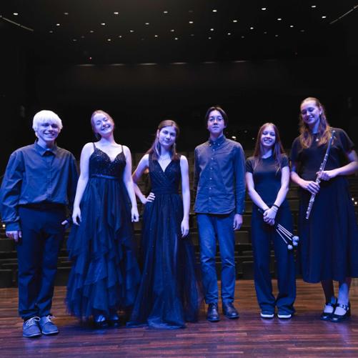 Zdjęcie przedstawia uczestników koncertu we wspólnym zdjęciu na scenie sali koncertowej filharmonii