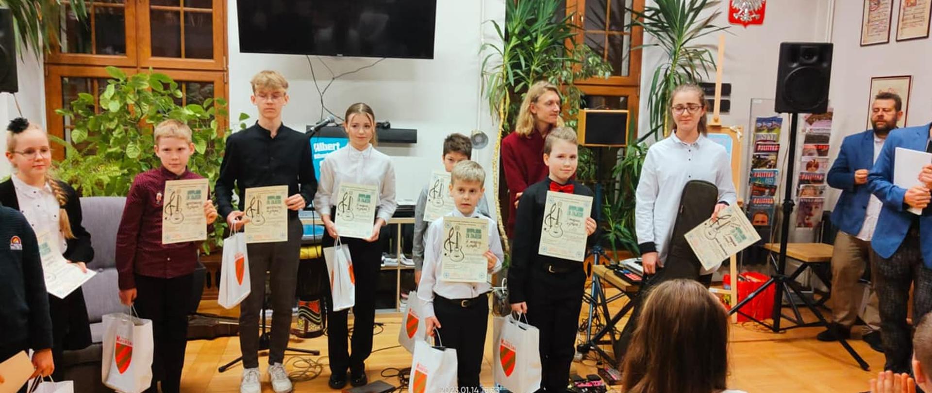 Na zdjęciu grupa uczniów trzymających dyplomy, zdjęcie wykonane w Bystrzyckiej Szkole muzycznej podczas Ogólnopolskiego Kolędowy Konkursu Gitarowego - 14.01.2023