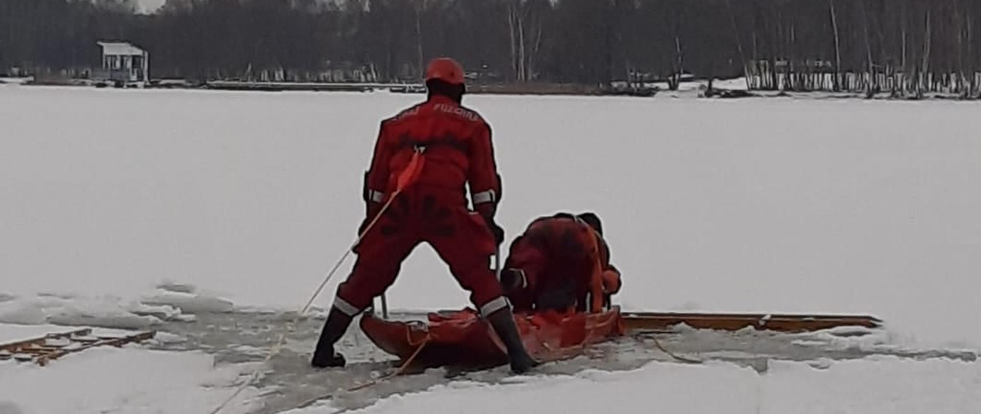Na zdjęciu widać strażaków ćwiczących ewakuację poszkodowanego z lodu.