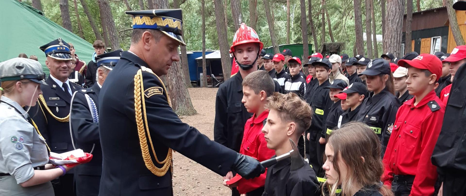 Ślubowanie strażaków MDP przez generała PSP ŚKW PSP podczas zbiórki w lesie na obozowisku MDP.