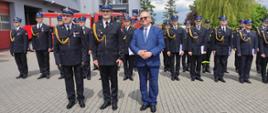 Zdjęcie przedstawia strażaków, którzy stoją na placu przed komendą podczas uroczystości obchodów dnia strażaka. 