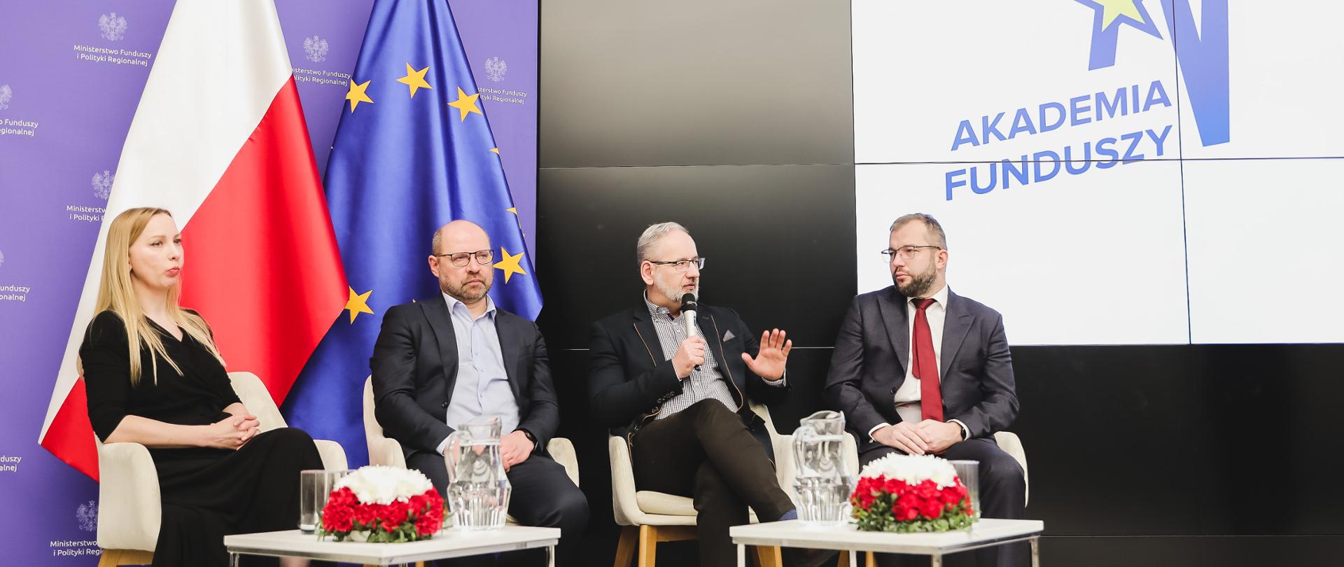 Cztery osoby siedzą na scenie.