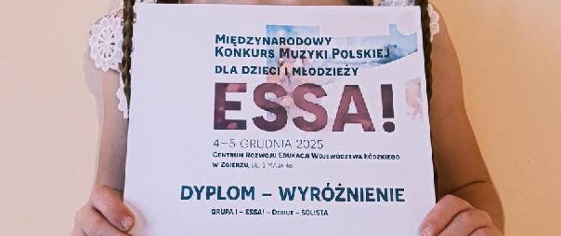 Na zdjęciu jest uczennica trzymająca dyplom z wyróżnieniem za Międzynarodowy konkurs Muzyki Polskiej dla dzieci i młodzieży ESSA!