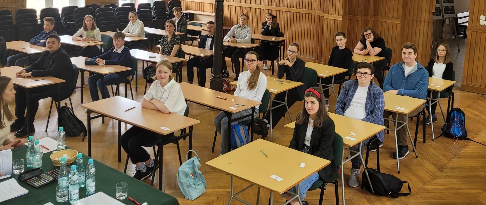 Fotografia przedstawia uczniów siedzących w ławkach podczas IX Międzyszkolnego Konkursu Wiedzy o Muzyce im. Korneliusza Ejsmonta