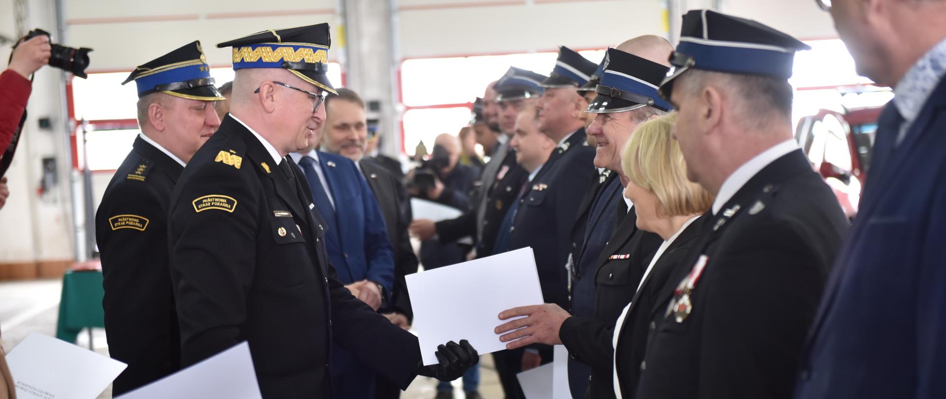 Zastępca komendanta głównego PSP wraz z łódzkim komendantem wojewódzkim wręczają decyzje druhom OSP 