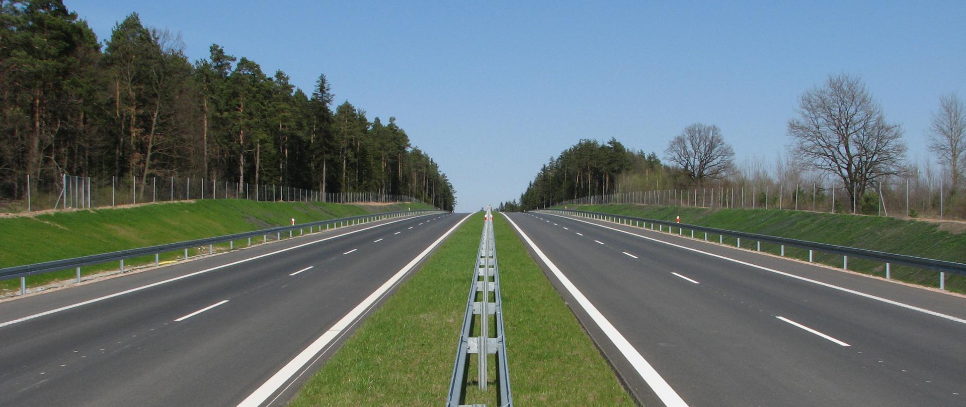 Droga ekspresowa - zdjęcie poglądowe, dwie jezdnie, zielony pas rozdziału z barierami, przy drodze las