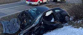Uszkodzone samochody w przydrożnym rowie za nimi samochody ratownicze