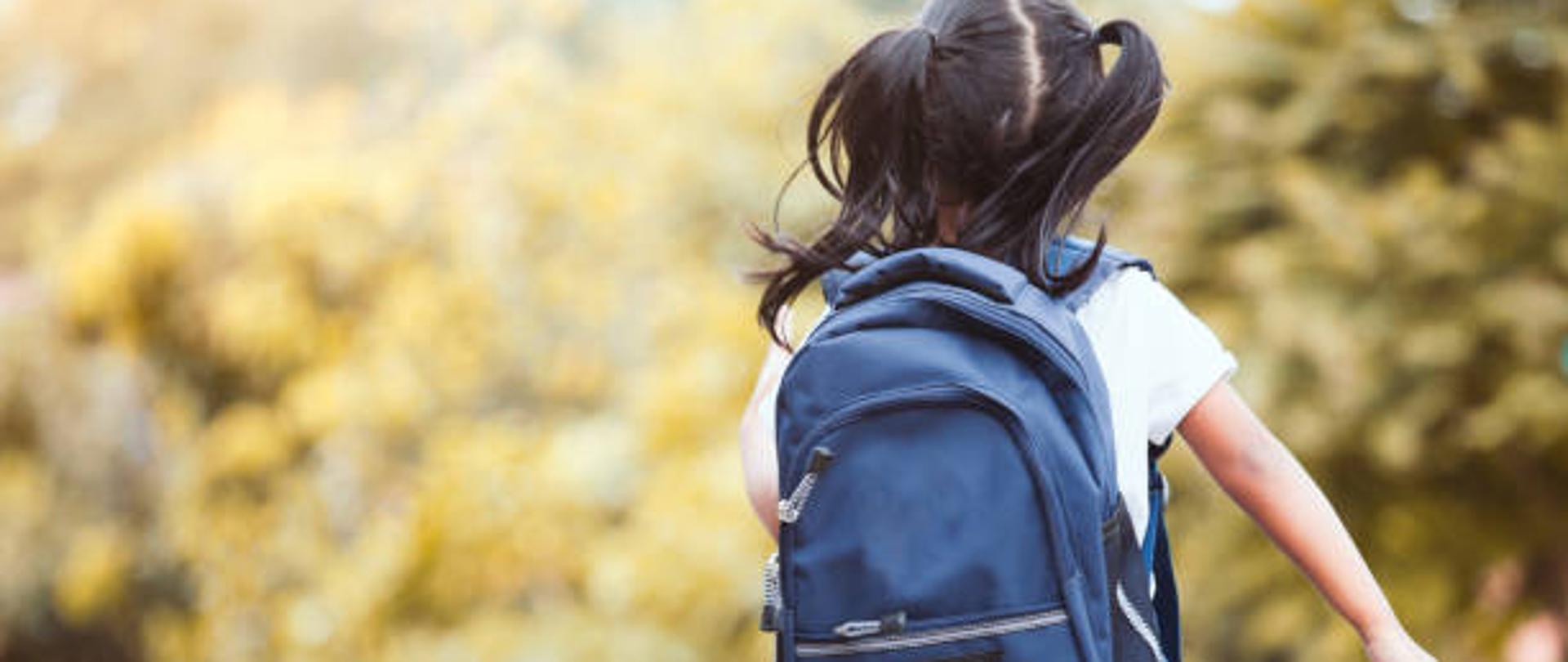Na zdjęciu widać dziewczynkę z plecakiem która idzie do szkoły 