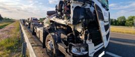 Kolizja dwóch cieżarówek. Droga ekspresowa S5 pomiędzy węzłami Bojanowo i Rawicz. Na pasie awaryjnym stoi ciężarowa scania z przyczepą. Bardzo mocno jest zniszczona kabina pojazdu. Za zestawem stoi wóz straży pożarnej i strażacy.