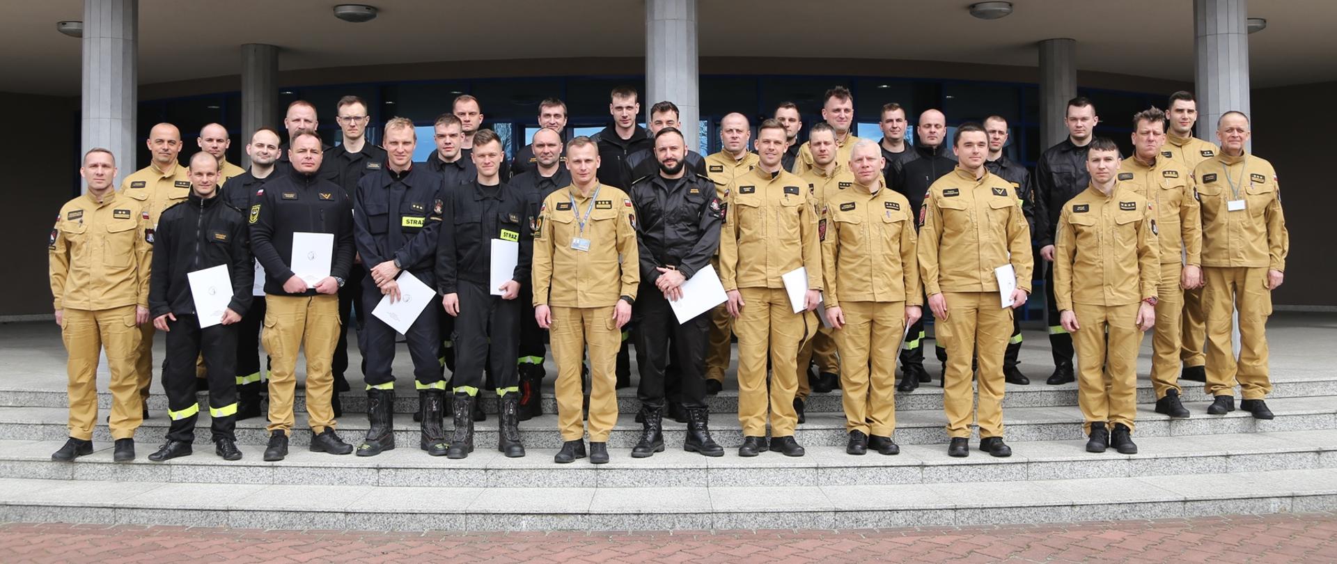 Grupowe zdjęcie uczestników warsztatów (27 osób) w towarzystwie Zastępcy Komendanta Centralnej Szkoły PSP oraz pięciu oficerów CS PSP