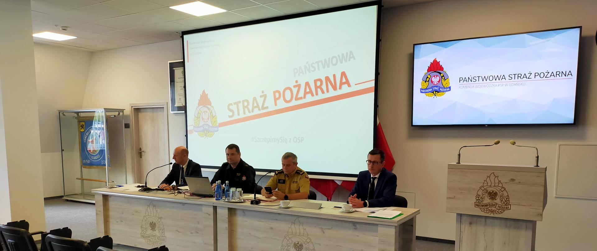 Pomorski komendant wojewódzki PSP, funkcjonariusz KW PSP, przedstawiciel Pomorskiego Oddziału Narodowego Funduszu Zdrowia oraz pełnomocnik wojewody pomorskiego ds. Narodowego Programu Szczepień uczestniczą w wideokonferencji z jednostkami ochrony przeciwpożarowej oraz ochotniczymi strażami pożarnymi - temat program "Szczepimy Się z OSP".