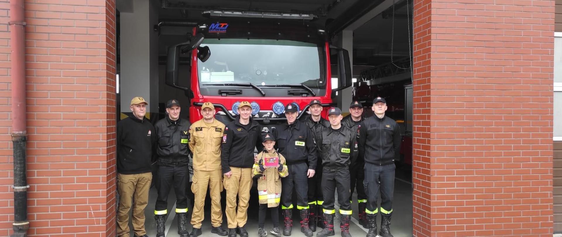 zmiana służbowa podczas zdjęcia grupowego z małym strażakiem