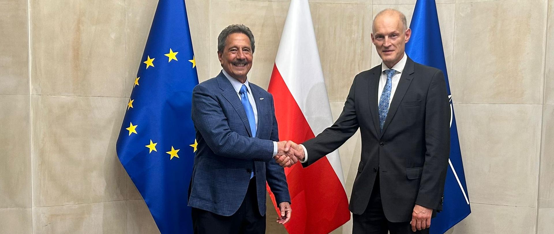 Undersecretary of State Wojciech Zajączkowski shaking hands with a Honduran minister. Three flags are visible in the background