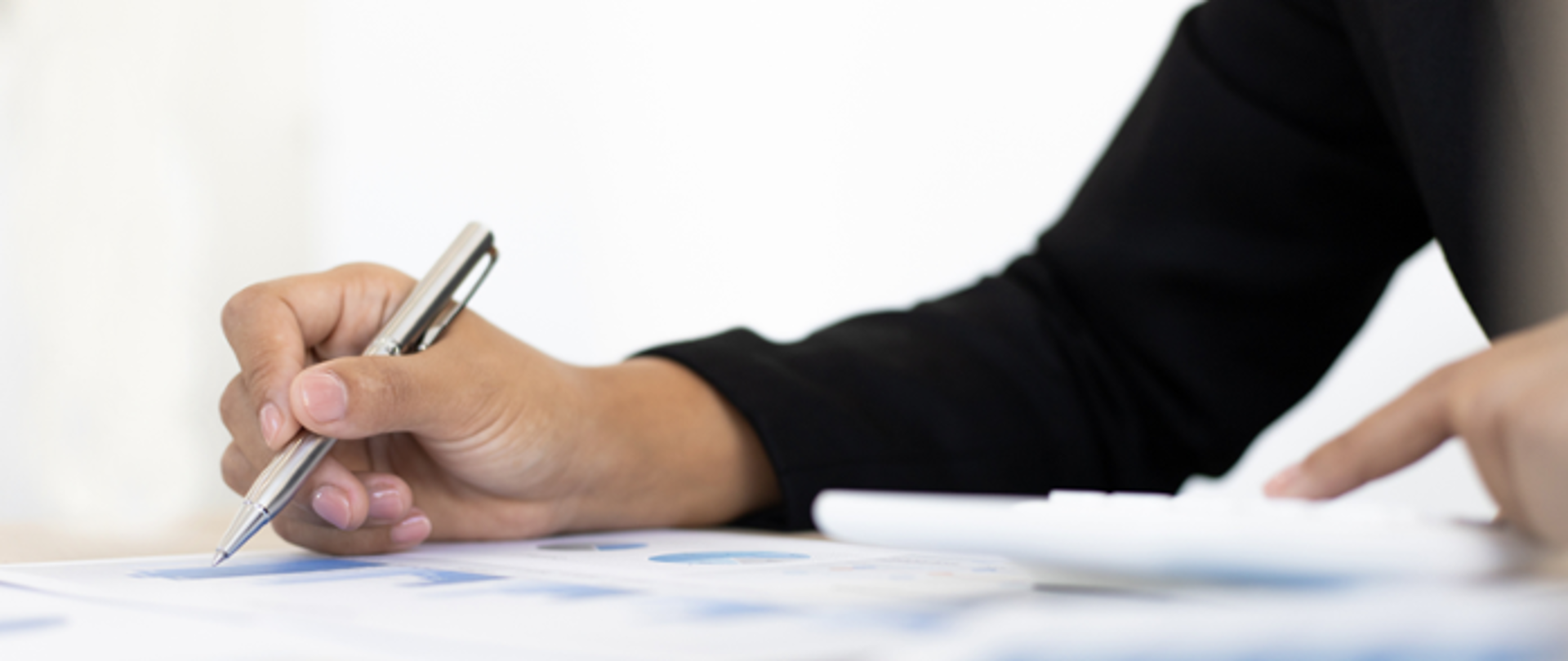 Damska dłoń trzyma długopis i wypełnia formularz