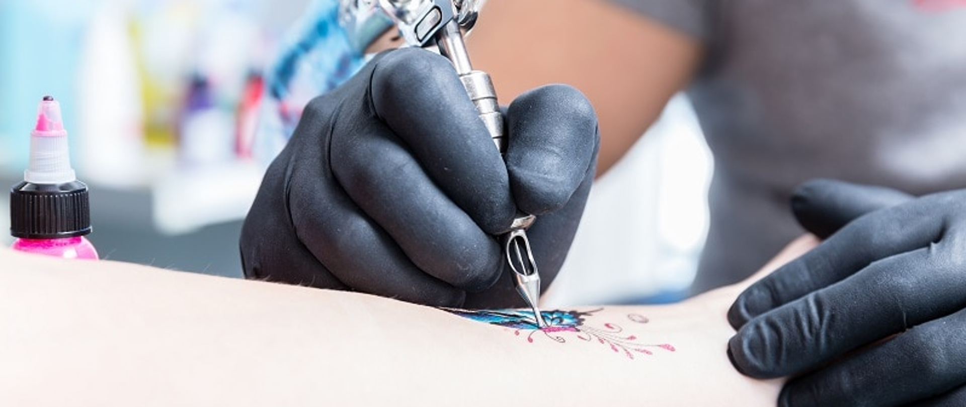 Tatuażysta wykonuje tatuarz na wewnętrznej stronie ręki