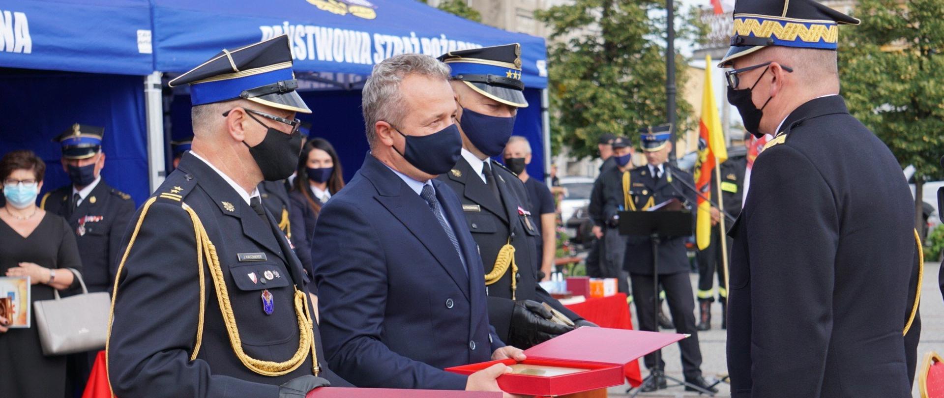 Mężczyźni w mundurach. Wojewoda wręcza gratulacje. 