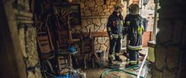 Na zdjęciu strażacy w zalanym pomieszczeniu po wypompowaniu wody