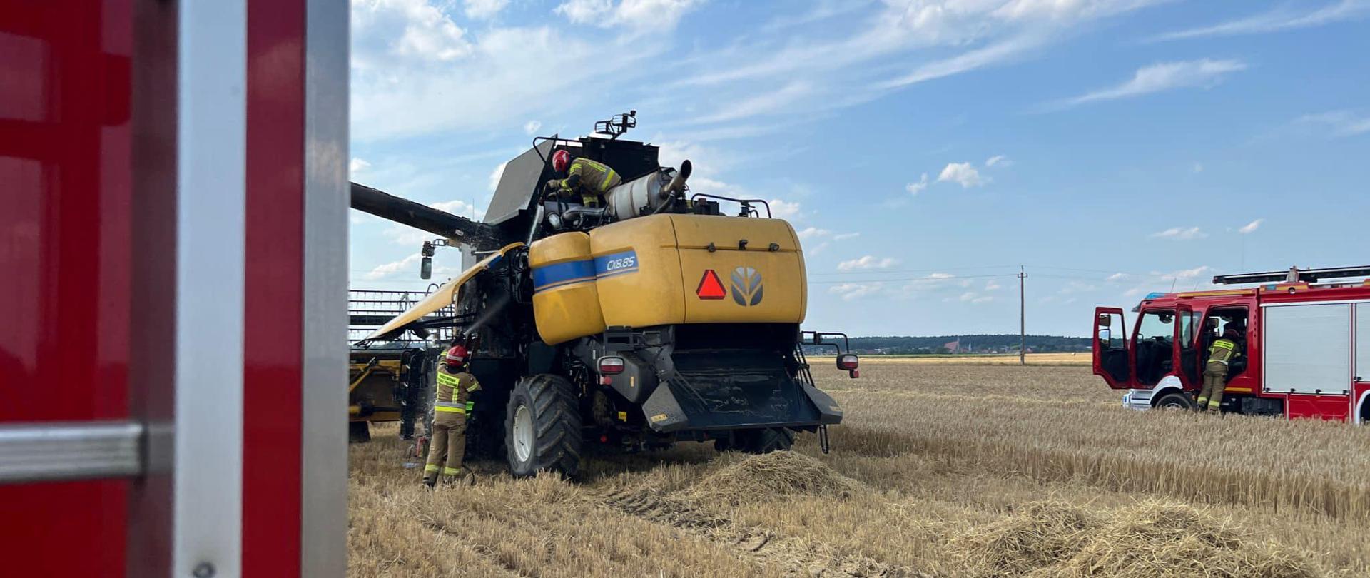 Na zdjęciu znajduje się kombajn oraz dwa samochody pożarnicze na polu 