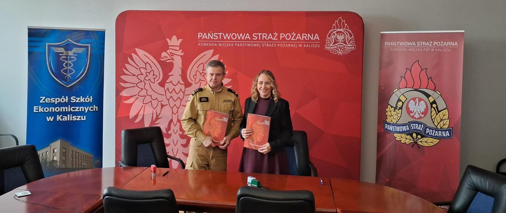 Komendant oraz Pani dyrektor na tle banera PSP.
