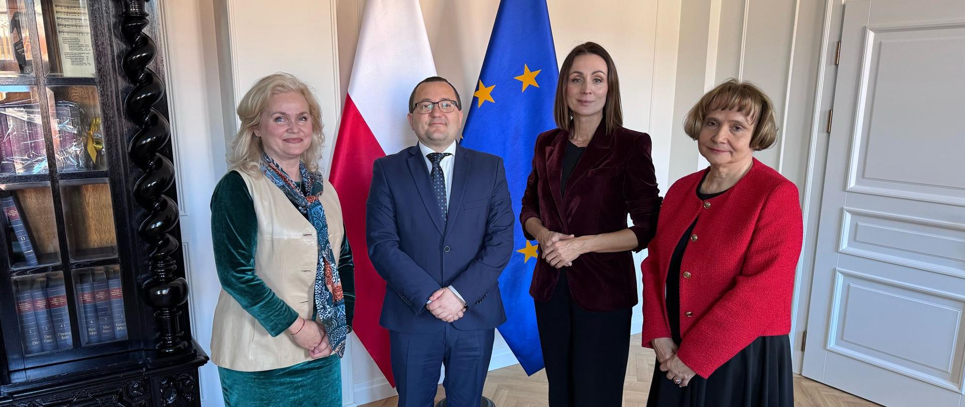 cztery osoby stoją na tle flagi Polski i UE