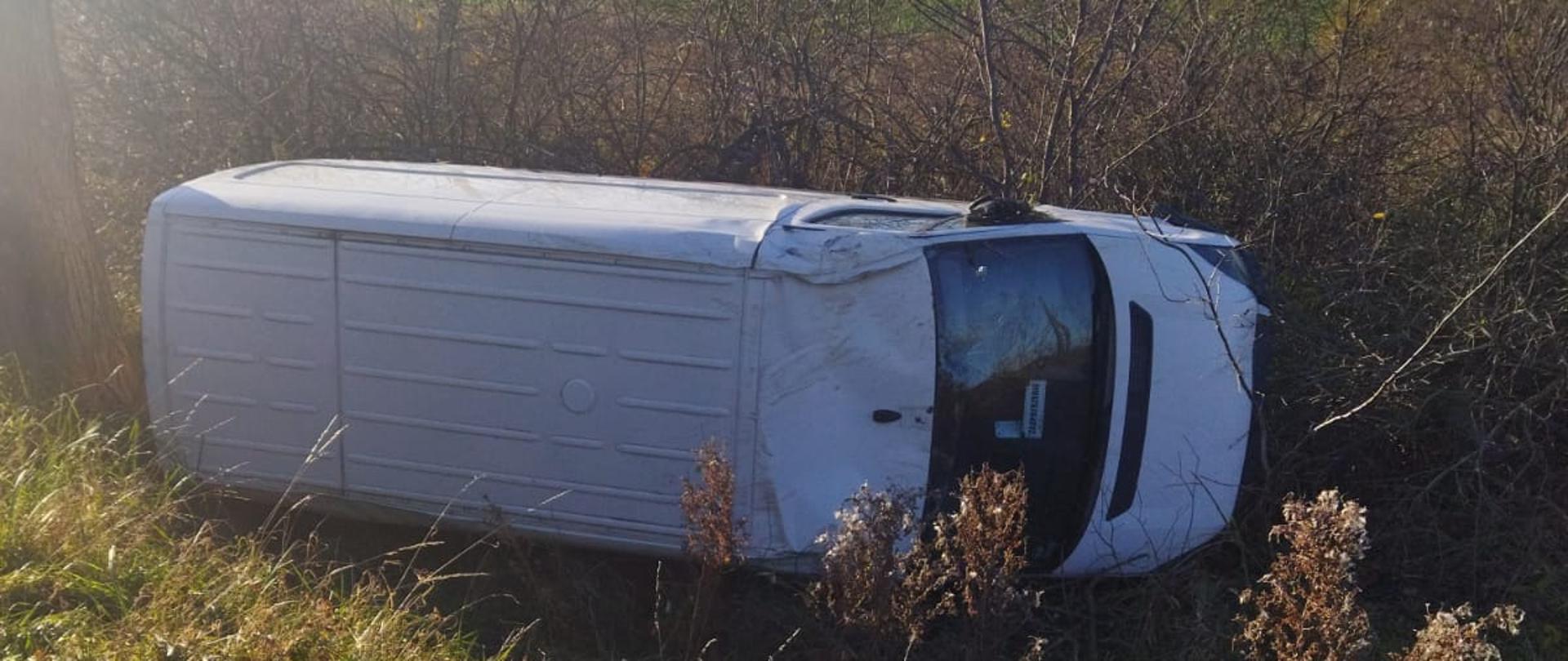 Samochód dostawczy leży na boku w rowie