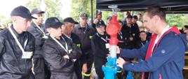 Strażacy obserwują wykład na temat hydrantów prowadzony przez osobę cywilną.