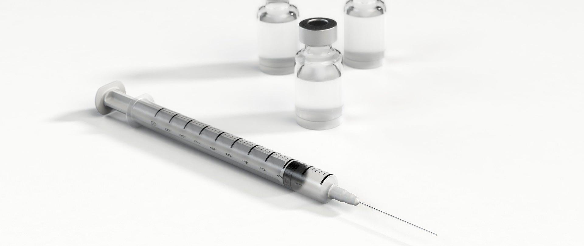 Zdjęcie przedstawia strzykawkę oraz ampułki z lekami.