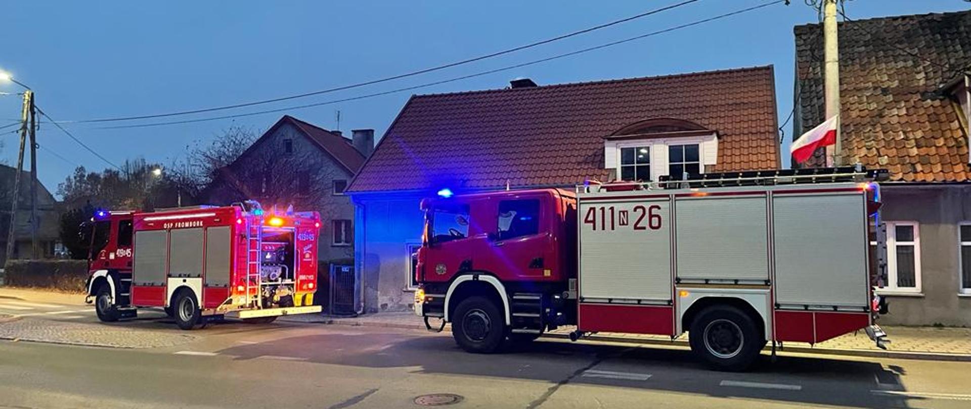 Na drodze ustawione dwa duże czerwone samochody strażackie.