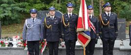 Na zdjęciu od lewej strony widzimy: oficera Policji, Komendanta Centralnej Szkoły PSP oraz poczet sztandarowy (trzech kadetów) Centralnej Szkoły stojących przed pomnikiem upamiętniającym żołnierzy 7 Dywizji Piechoty Armii "Kraków"