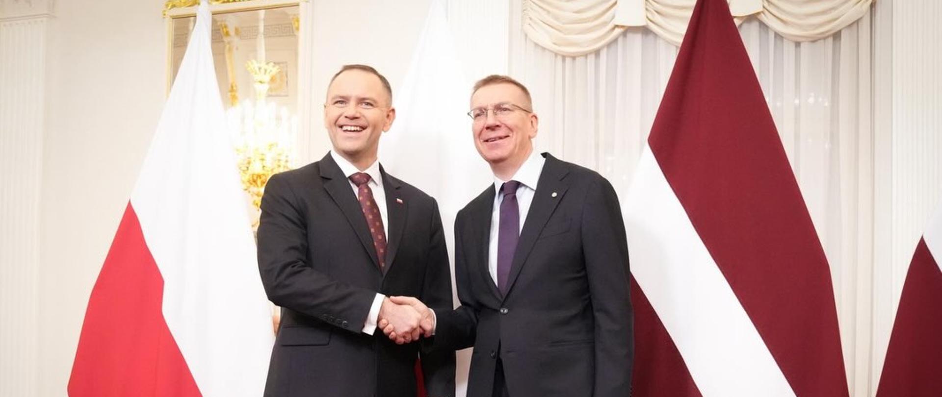 Prezydent Karol Nawrocki podczas spotkania z prezydentem Edgarsem Rinkēvičsem uścisnęli sobie dłonie na tle flag Polski i Łotwy.