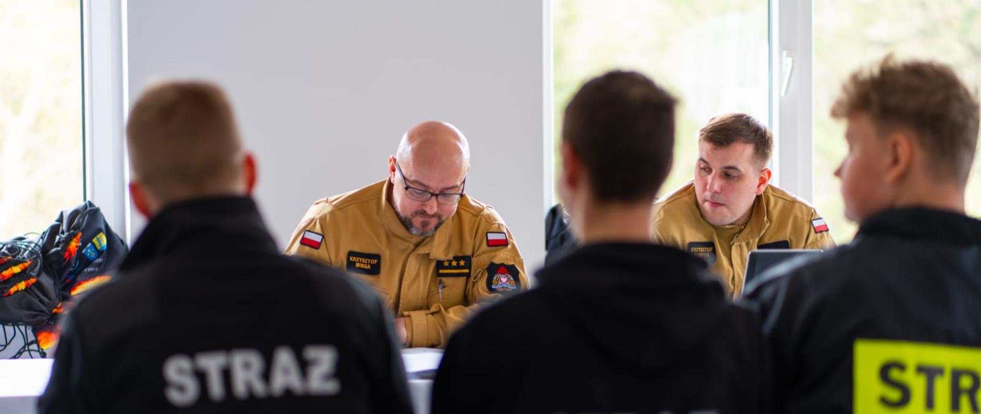 Na zdjęciu przedstawiony jest etap pytań ustnych do uczestników. Uczestnicy siedzą obok siebie plecami do fotografa, natomiast naprzeciwko siedzi komisja w składzie p.o Z-ca Komendanta Powiatowego PSP w Pucku Pan Krzysztof MInga oraz asp. Krzysztof Rumpca . 